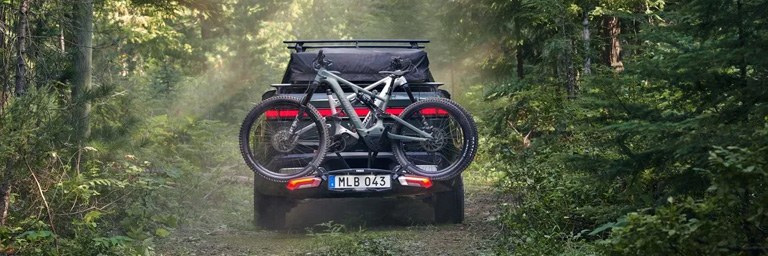 Thule bike rack holding a bike on the back of a car in the forest